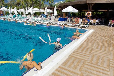 Alanya, Turkey - October 05, 2018. A group of people is engaged in aqua aerobics in the blue clear water of the pool at Kirman Sidera Luxury Spa. Fitness concept, summer vacation, sport, tourismのeditorial素材