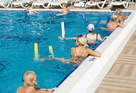 Alanya, Turkey - October 05, 2018. A group of people is engaged in aqua aerobics in the blue clear water of the pool at Kirman Sidera Luxury Spa. Fitness concept, summer vacation, sport, tourismのeditorial素材