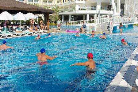 Alanya, Turkey - October 05, 2018. A group of people plays water polo in the blue clear water of the Kirman Sidera Luxury hotel pool. Fitness concept, summer vacation, sport, tourismのeditorial素材