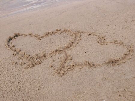 Figure of two hearts on sand of a beach       の写真素材