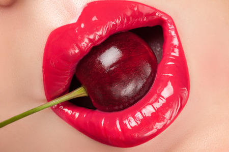 Lip gloss painted red with cherries in the mouth.の写真素材