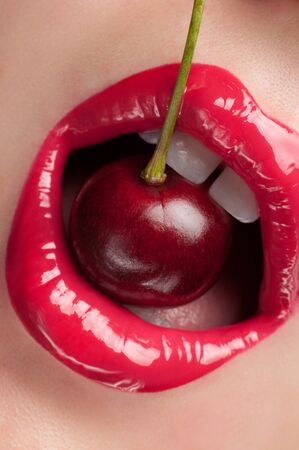 Lip gloss painted red with cherries in the mouth.の写真素材