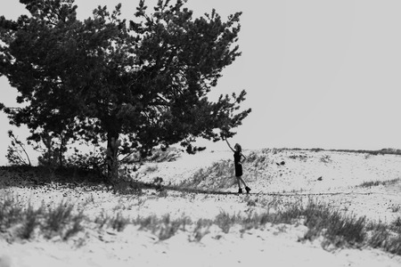 Fashion shot in the desert. A beautiful sexy girl in a black dress. The girl in the desert in fashionable clothes for advertising.の写真素材