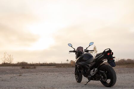 One black motorcycle in the desert in autumn time.