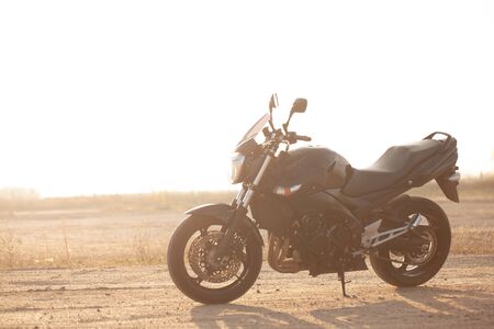 One black motorcycle in the desert in autumn time.