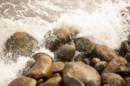 The sea beats against stones and splashes fly.の写真素材