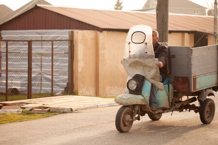 Unusual old tricycle rides on the road.の写真素材
