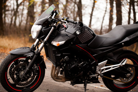 Black stylish sport motorcycle in autumn forest.のeditorial素材