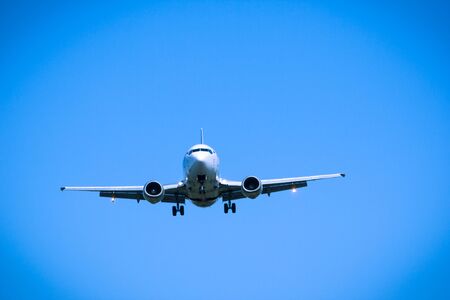 Jet airplane flying overhead close-up on a blue sky backgroundの写真素材
