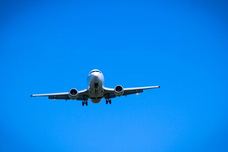 Jet airplane flying overhead close-up on a blue sky backgroundの写真素材