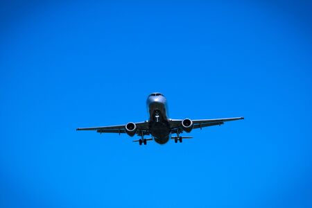 Jet airplane flying overhead close-up on a blue sky backgroundの写真素材