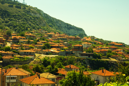View on red tiled roofs of small town among hills and meadows under clean blue skyの写真素材