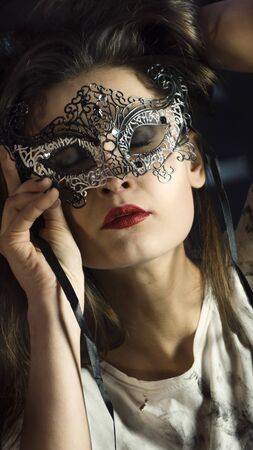 Beauty model wearing venetian masquerade carnival mask. Masquerade party. Luxurious glamor portrait, femme fatale in carnival mask. Red lipstickの写真素材