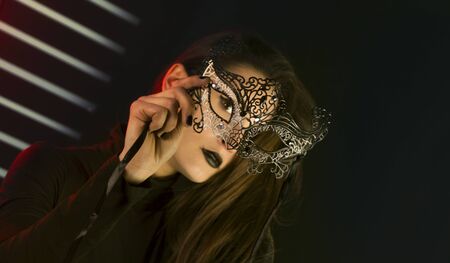 Beauty model wearing venetian masquerade carnival mask. Masquerade party. Luxurious glamor portrait, femme fatale in carnival mask. Black lipstickの写真素材