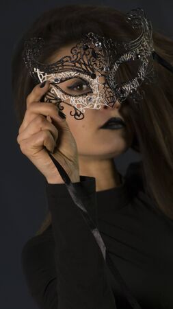 Beauty model wearing venetian masquerade carnival mask. Masquerade party. Luxurious glamor portrait, femme fatale in carnival mask. Black lipstickの写真素材