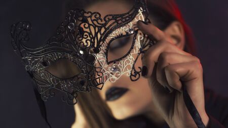Beauty model wearing venetian masquerade carnival mask. Masquerade party. Luxurious glamor portrait, femme fatale in carnival mask. Black lipstickの写真素材