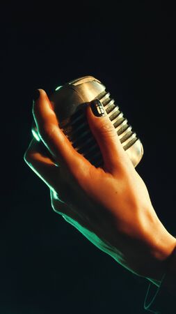Close up of beautiful female woman singer mouth with red lips singing into a vintage microphone in a night clubの写真素材