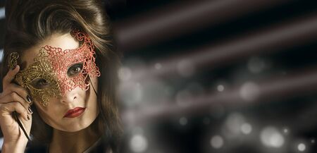Beauty glamor lady wearing venetian masquerade carnival mask at party over holiday glowing darck background. Glamor woman with perfect makeup and hairstyle. Widescreenの写真素材