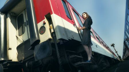 Beautiful woman in high heels and retro dress walking along on the railway station.の写真素材