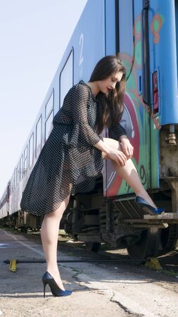 Beautiful woman in high heels and retro dress walking along on the railway station.の写真素材