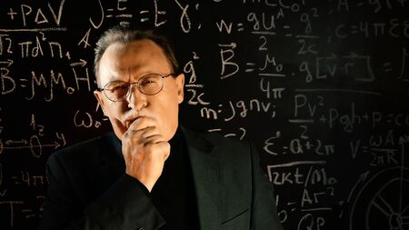 Medium shot of male university professor. Math formulas on blackboard. Knowledge and On-line education concept.の写真素材