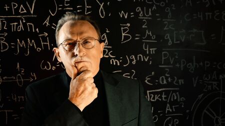 Medium shot of male university professor. Math formulas on blackboard. Knowledge and On-line education concept.の写真素材