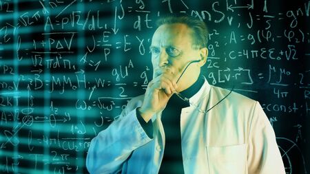 Medium shot of male university professor in white coat conducting experiments with augmented reality. Math formulas on blackboard. Knowledge and On-line education concept.の写真素材