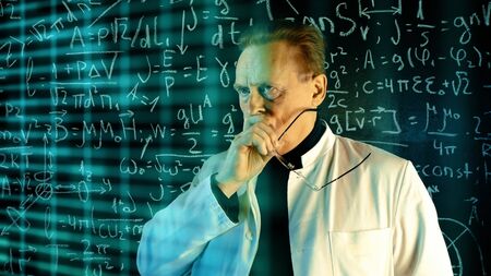 Medium shot of male university professor in white coat conducting experiments with augmented reality. Math formulas on blackboard. Knowledge and On-line education concept.の写真素材