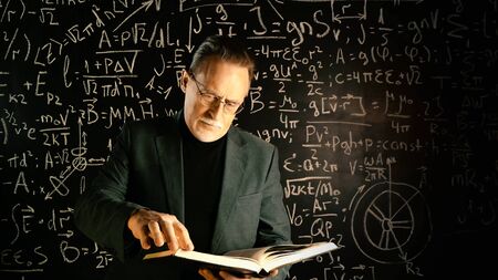 Medium shot of male university professor. Math formulas on blackboard. Knowledge and On-line education concept.の写真素材