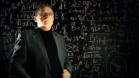 Medium shot of male university professor. Math formulas on blackboard. Knowledge and On-line education concept.の写真素材