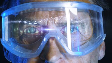 Mature doctor in augmented reality glasses on dark background. Close up portrait elderly scientist in high tech laboratory. Handsome gray haired doctor in augmented reality glasses looking at screen.の写真素材