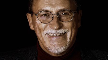 Close up isolated portrait of senior man in glasses on black backgroundの写真素材
