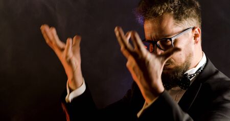 Emotional conductor on dark background. Man conducting an orchestra.の写真素材