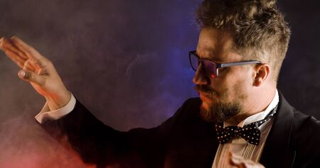 Emotional conductor on dark background. Man conducting an orchestra.の写真素材