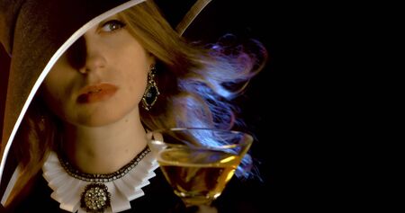 Portrait of vintage woman in classic hat drinking champagne on black background. Retro styling girl holding glass of champagne in studio. Retro portrait of a fashion elegance model. Luxury party.の写真素材