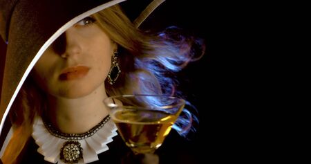 Portrait of vintage woman in classic hat drinking champagne on black background. Retro styling girl holding glass of champagne in studio. Retro portrait of a fashion elegance model. Luxury party.の写真素材