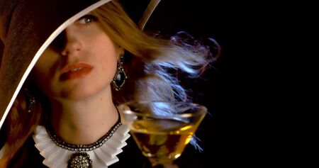 Portrait of vintage woman in classic hat drinking champagne on black background. Retro styling girl holding glass of champagne in studio. Retro portrait of a fashion elegance model. Luxury party.の写真素材