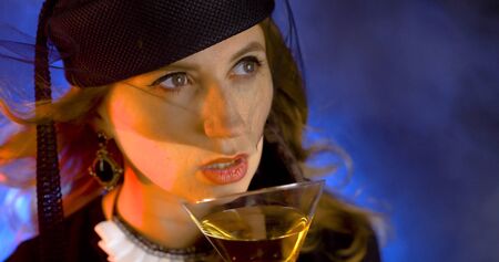 Portrait of vintage woman in classic hat drinking champagne on black background. Retro styling girl holding glass of champagne in studio. Retro portrait of a fashion elegance model. Luxury party.の写真素材