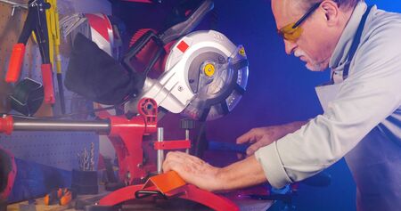 Senior craftsman working in his workshop. Portrait of pleasing old man working in modern industrial workshop. Close up shot of old mechanic master working in his workshop. Small business.の写真素材