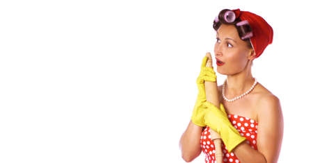 Cheerful housewife in pin up style with perfect hair and make up. Retro lady in a red dress and a yellow household gloves with a rolling pin. Housework, cleaning, cooking concept.の写真素材