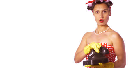 Wow face. Amazed housewife in pin up style speaks on the phone. Retro lady in a red dress and a yellow household gloves. Housework or cleaning concept.の写真素材