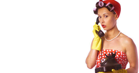 Wow face. Amazed housewife in pin up style speaks on the phone. Retro lady in a red dress and a yellow household gloves. Housework or cleaning concept.の写真素材