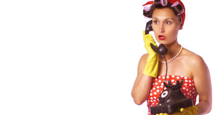 Wow face. Amazed housewife in pin up style speaks on the phone. Retro lady in a red dress and a yellow household gloves. Housework or cleaning concept.の写真素材