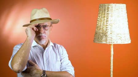 studio portrait of an old man looking at camera on a colorful wallの写真素材