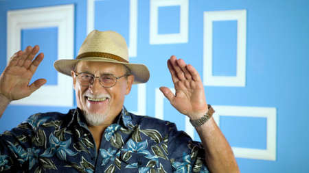 studio portrait of an old man looking at camera on a colorful wallの写真素材