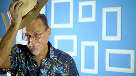 Studio portrait of an fashion old man in summer hawaiian shirts and straw hat looking at camera on a...