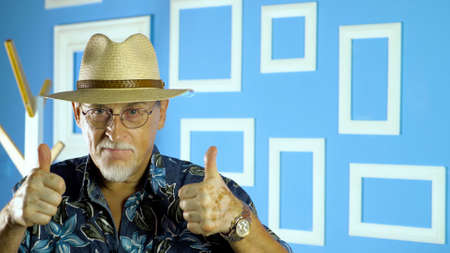 studio portrait of an old man looking at camera on a colorful wallの写真素材