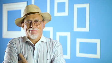 studio portrait of an old man looking at camera on a colorful wallの写真素材