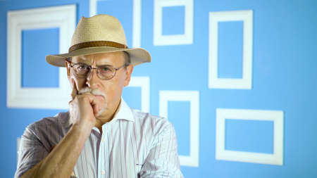 studio portrait of an old man looking at camera on a colorful wallの写真素材
