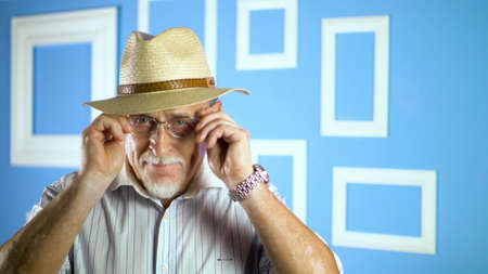 studio portrait of an old man looking at camera on a colorful wallの写真素材